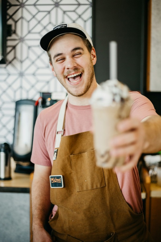 A barista serving a drink from behind the counter